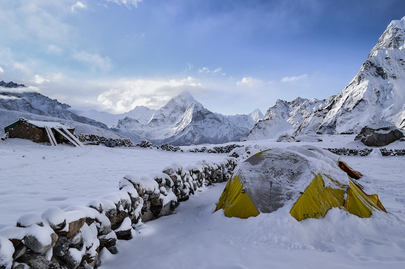 Jagged, snowy mountain peaks with tent in foreground