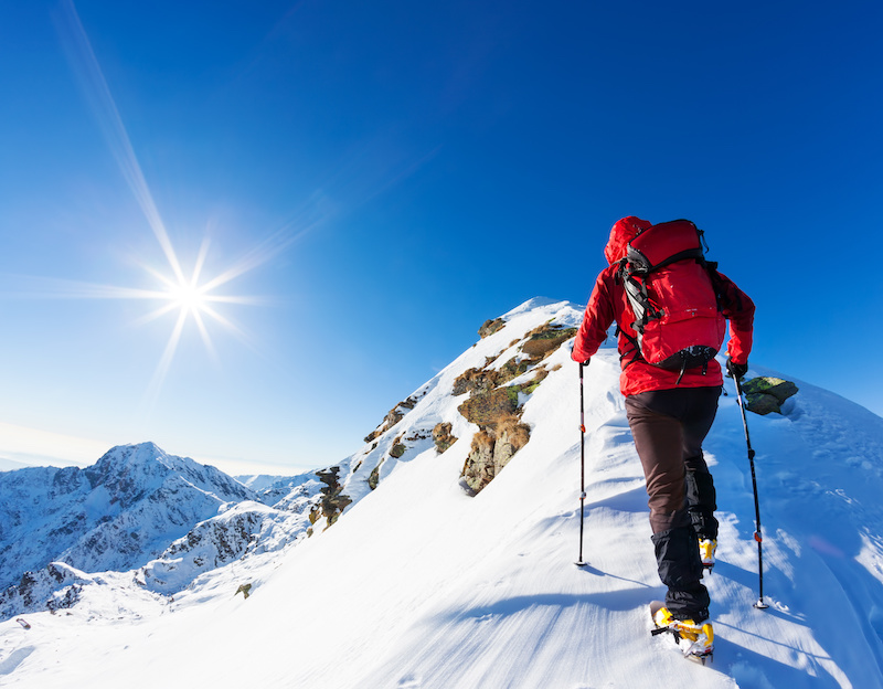hiker traversing snow ridgeline on a sunny day