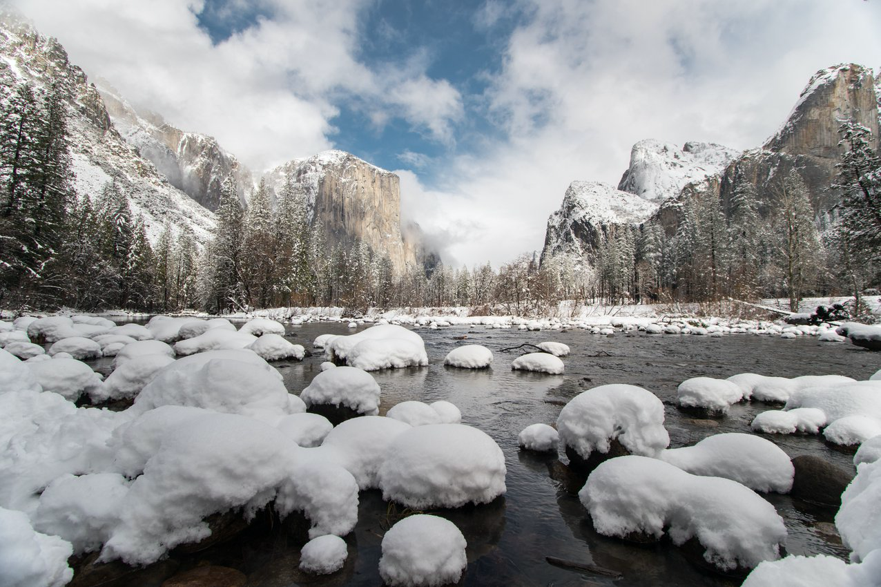 Snowy river rocks backdropped by snow covered El Capitan, Yosemite Valley's most prominent monolith.