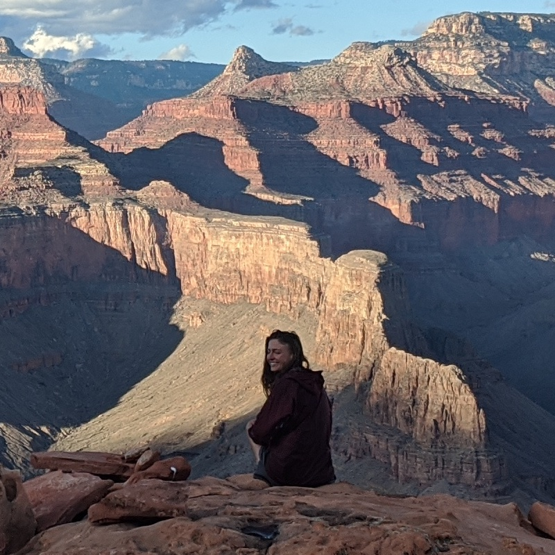 Sasha sitting on the rim overlooking a canyon