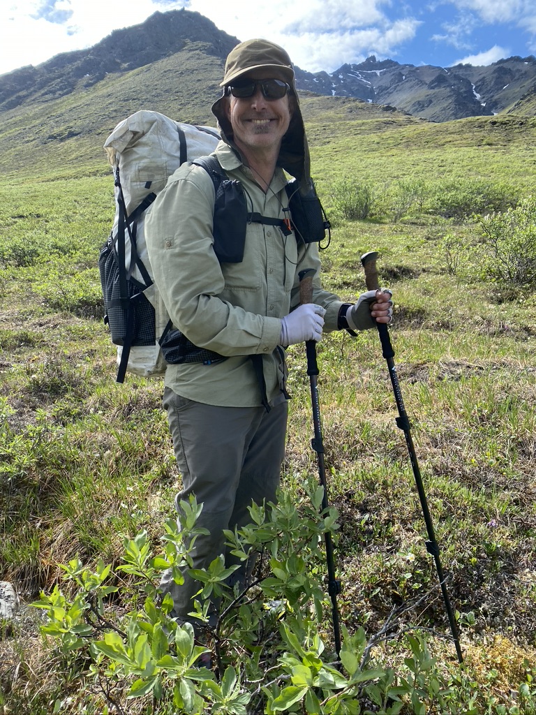 Adventure Alan Dixon wearing a backpack and holding trekking poles and smiling at the camera