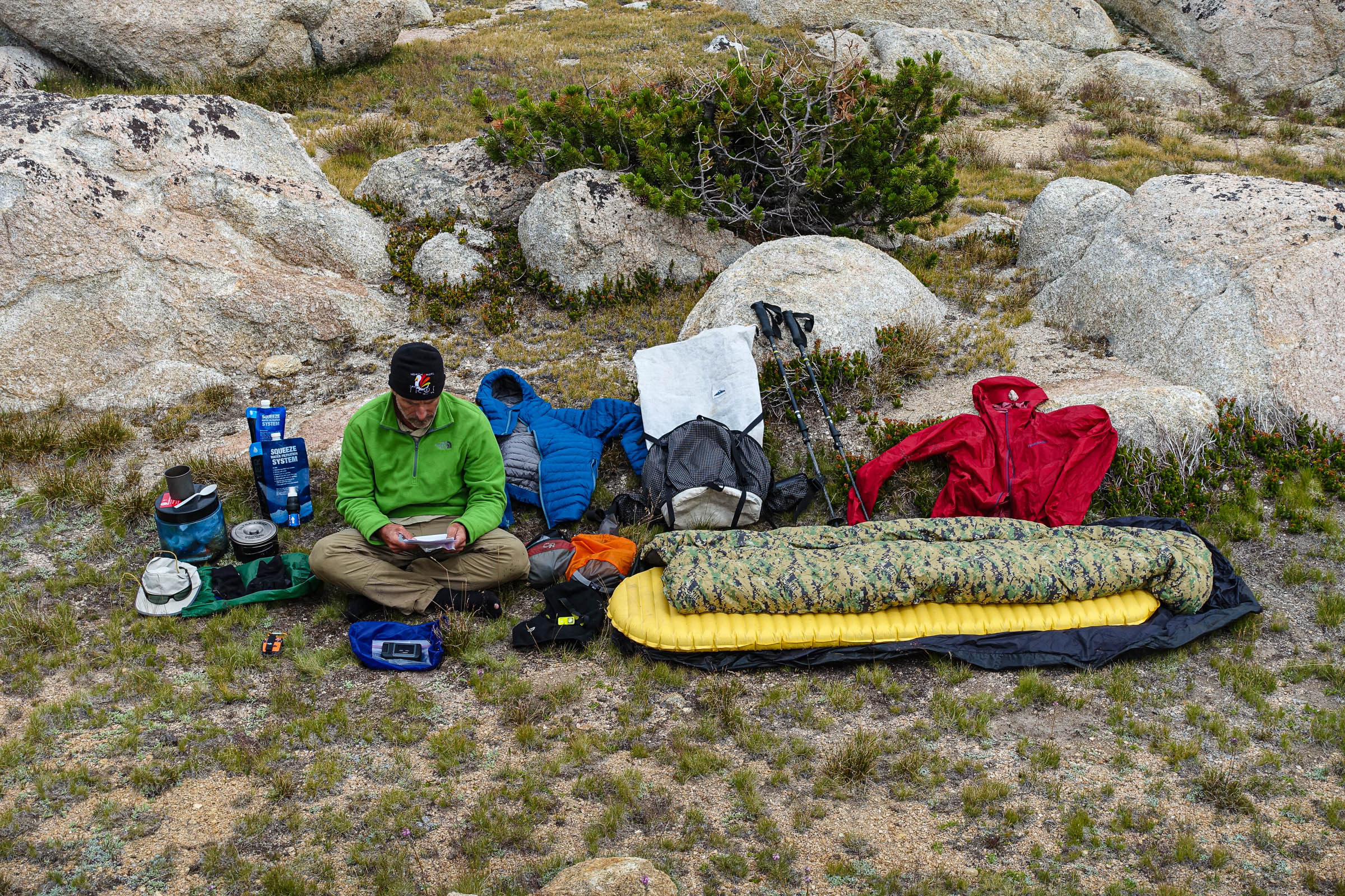 Adventure Alan sits in the backcountry with his gear spread out around him.