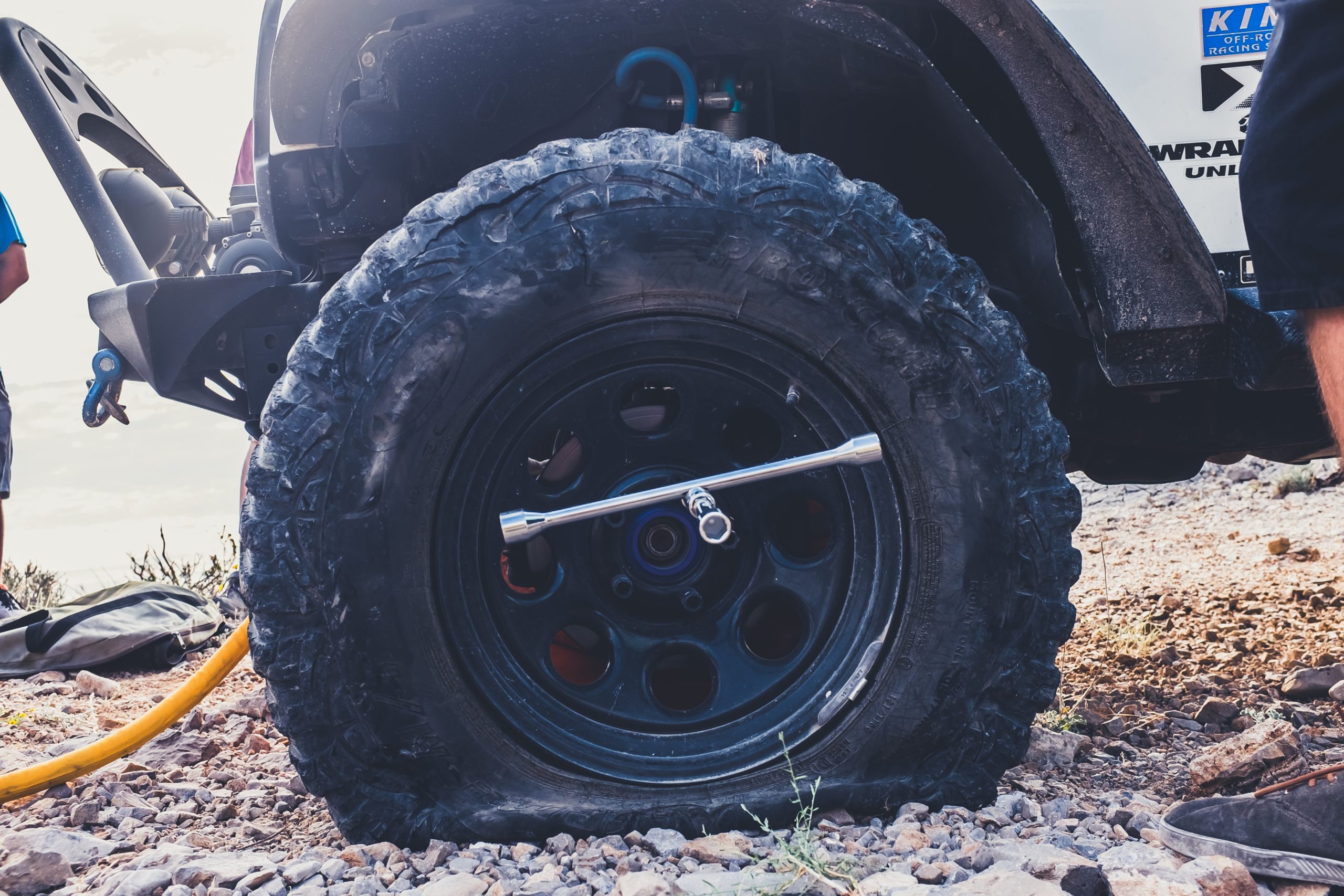 A close-up of vehicle shows a flat tire with a torque wrench wedged in the hub.