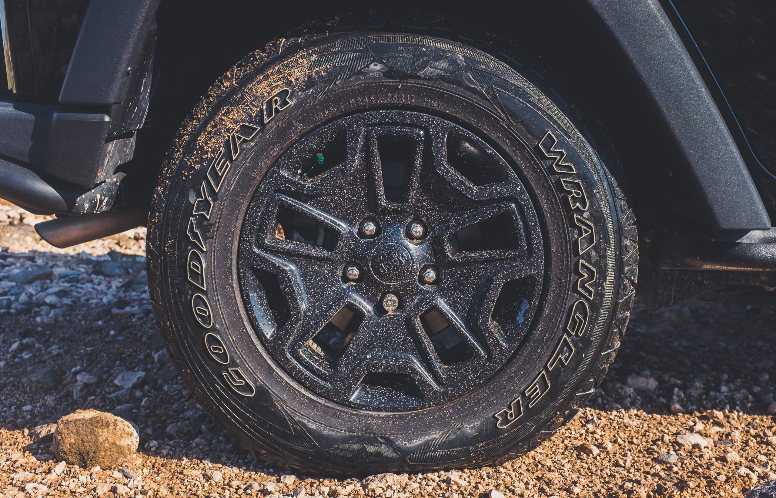 A close-up of a vehicle with flat tire on a dirt road.