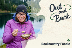 Backcountry Foodie smiles while eating a bowl of food in the backcountry.