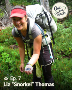 Snorkel smiles as she reaches out a hand filled with blueberries. She stands in a field, with a full backpacking pack on her back.