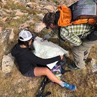 Two people pour over a paper map in the backcountry.