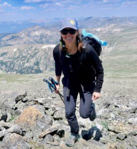 Mary smiles for the camera while backpacking through the alpine.