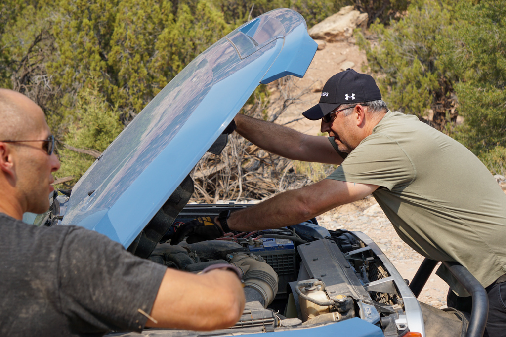 A man fixing a vehicle with the hood up.