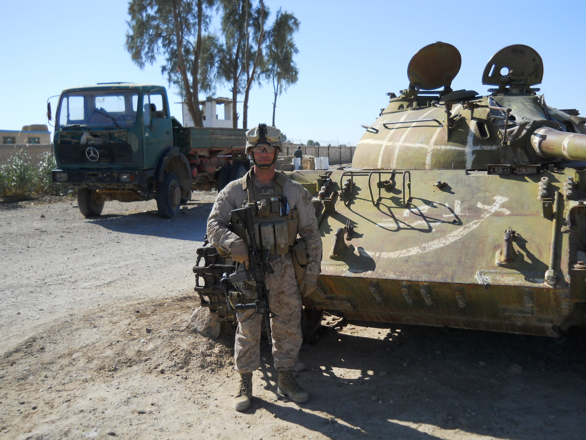 Sean Gobin stands in full combat gear in front of a military tank in the desert of south west Afghanistan.