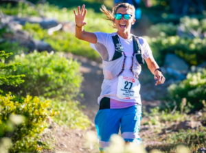 Courtney smiles and waves as she runs down the trail at Western States.