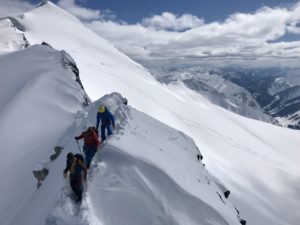 3 mountain guides hiking through snow terrain