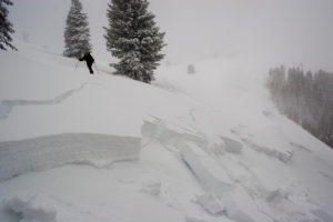 A skier crosses over the remnants of an avalanche slide.