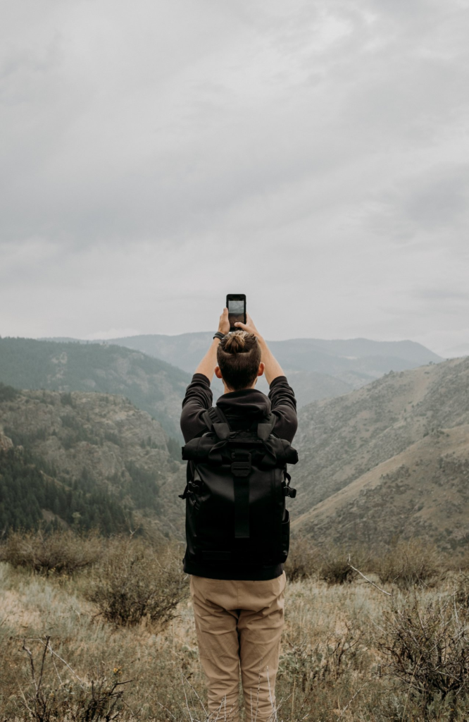 person holding there arms up to take a phone picture of a mountain range