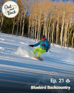 A splitboarder rides down a slope with aspens in the background. 