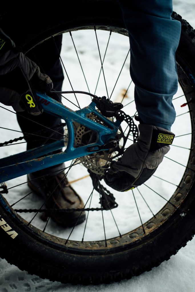 Hands in winter gloves adjust the cassette on a fat tire bike.