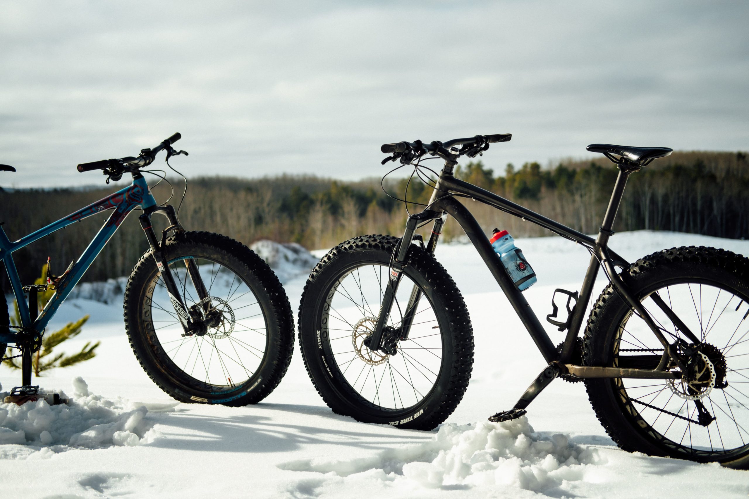 Two fat tire bikes face each other in the snow.