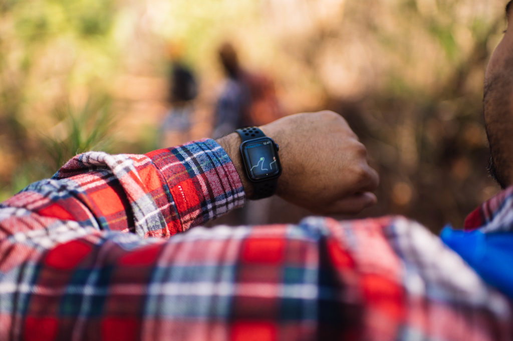 Person in red flannel holds up Apple Watch with Gaia GPS displaying position on watch route. 