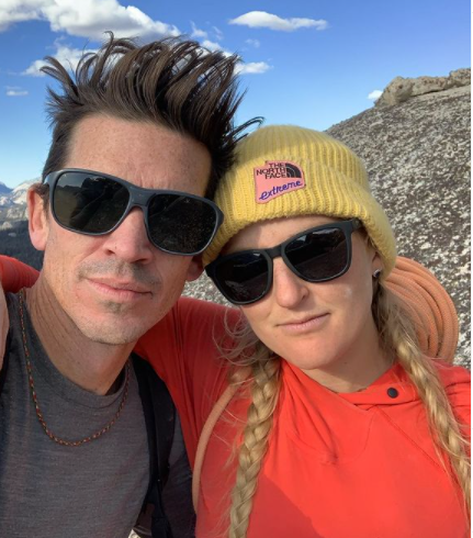 Adrian and Emily Harrington pose in a selfie. Emily's arm is wrapped around Adrien's shoulder.