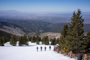 Four skiers skin up the mountain.