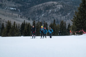 Five skiers skin up a ski slope.