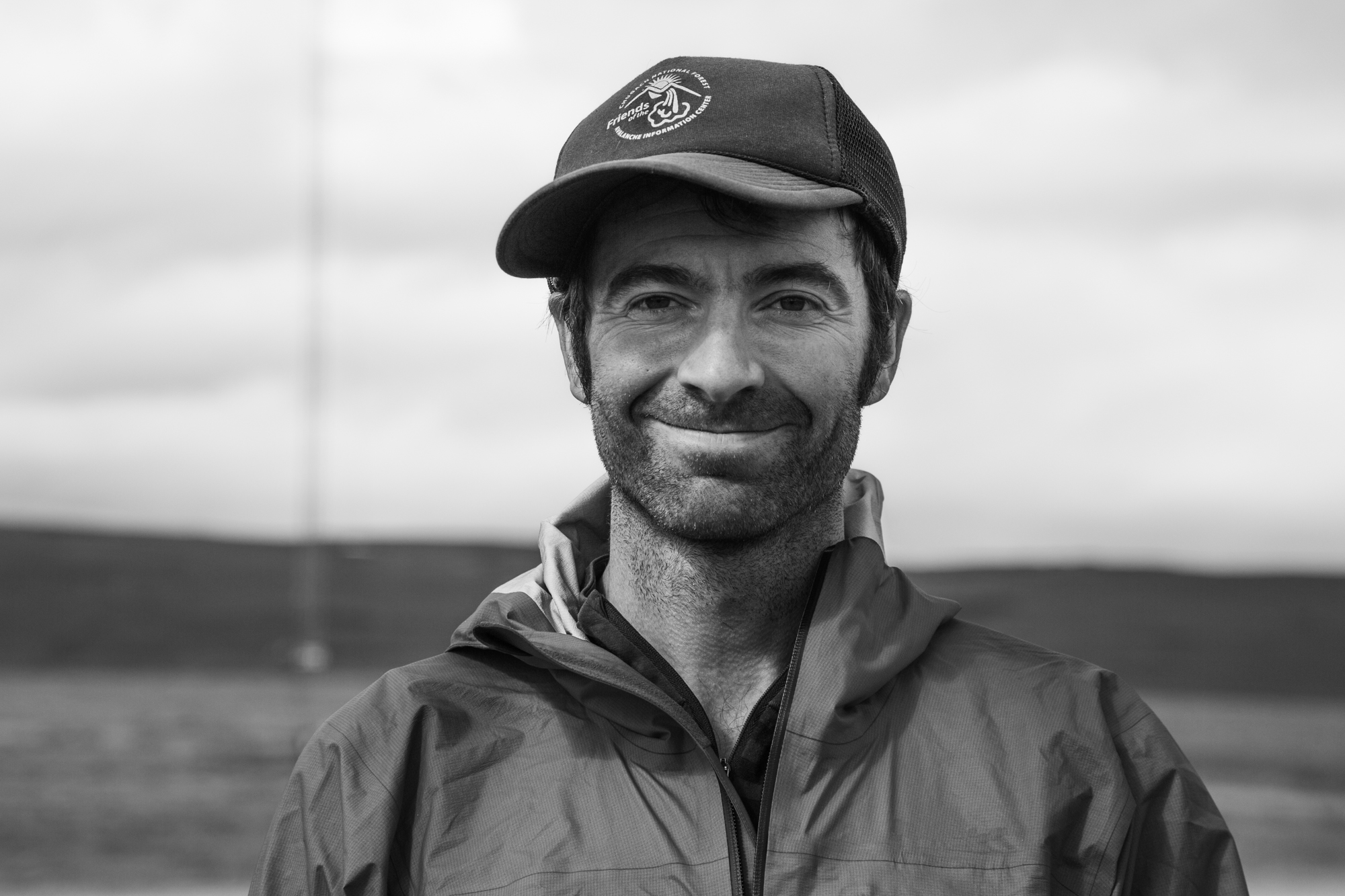 Profile image of Luc Mehl. He's smiling at the camera, wearing a trucker hat and a raincoat.