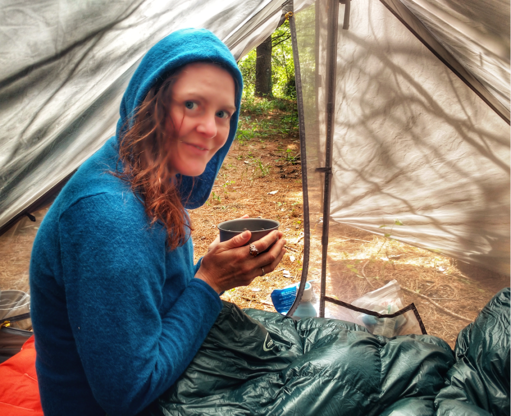 Heather Anderson sits with a cup of coffee in her tent.
