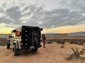 Brittany holds her son next to a fully rigged jeep. Sunset desert in the background.