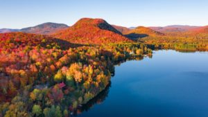 Aerial photo of fall foliage on a mountain by a lake (Photo: Aaron Macrae/Stocksy)