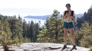 Hiker looks at phone in front of Lake Tahoe.